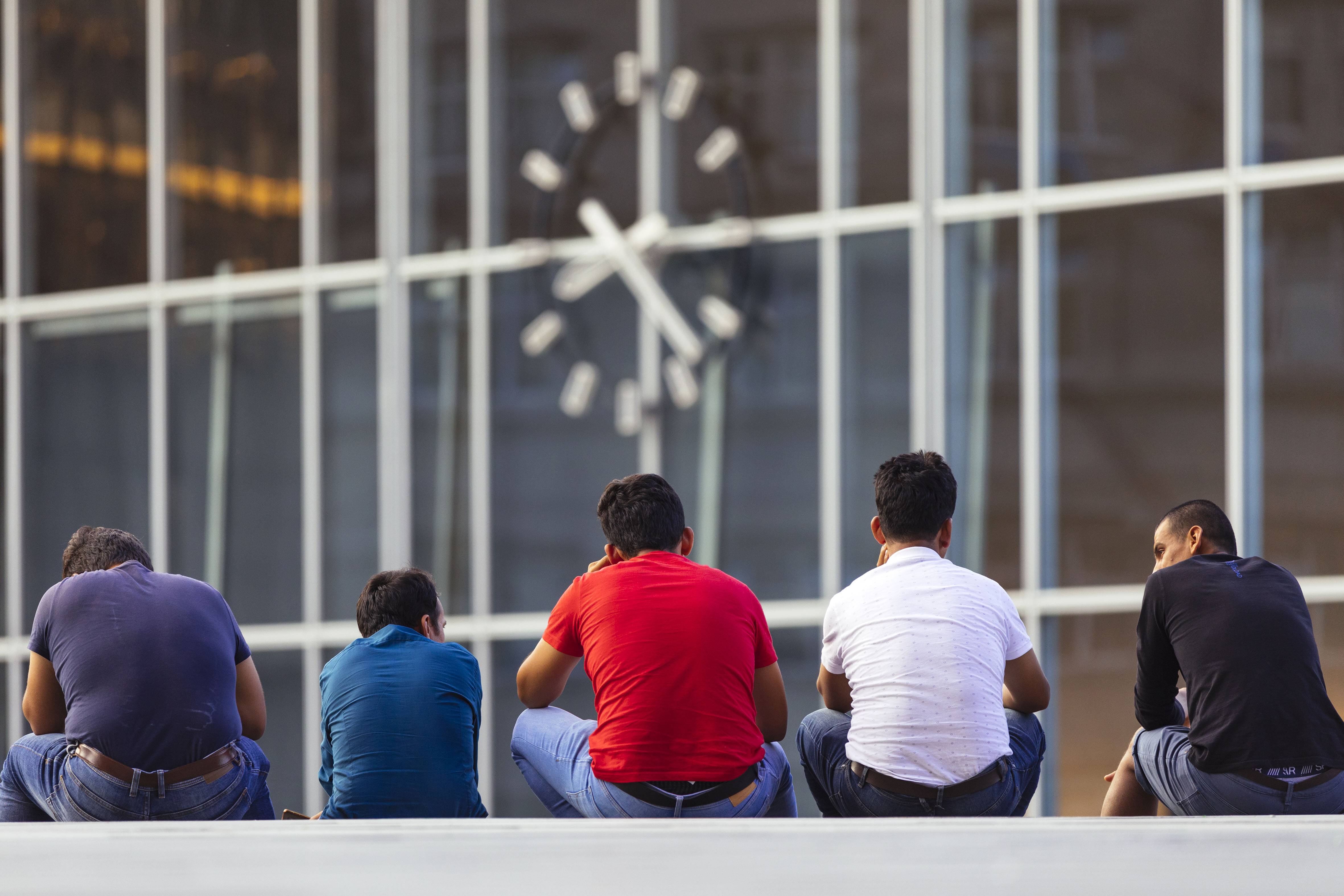 Migranten sitzen auf der Bahnhofstreppe am Kölner Hauptbahnhof.