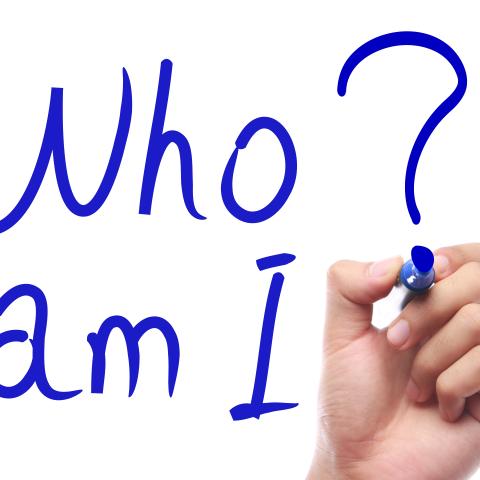 Hand mit Stift schreibt "Who am I?"