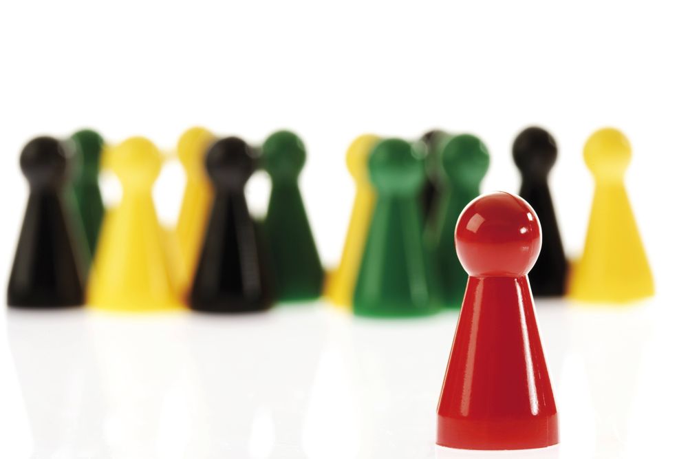 Einzelne rote Spielfigur vor andersfarbiger Gruppe