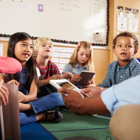 Grundschulklasse in der Runde sitzend mit Laptop