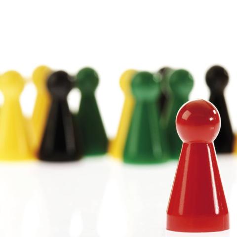 Einzelne rote Spielfigur vor andersfarbiger Gruppe